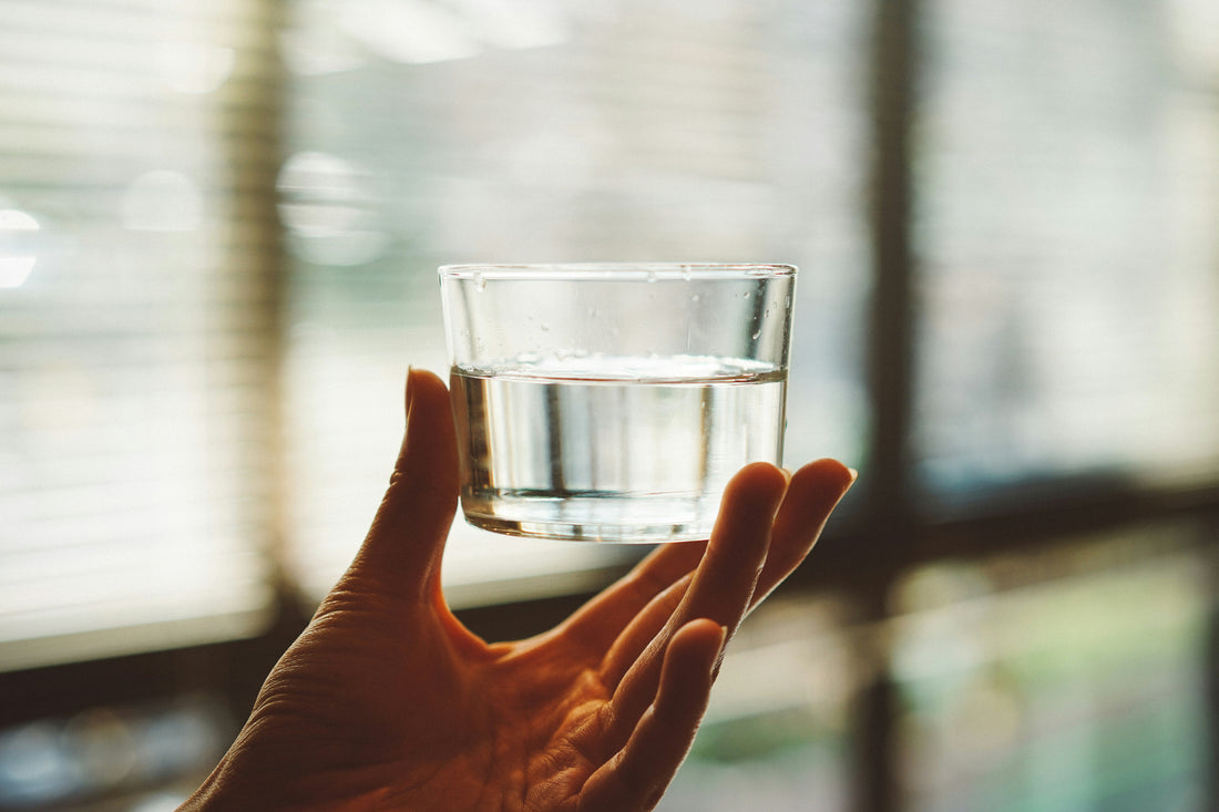 A hand holding a glass of water