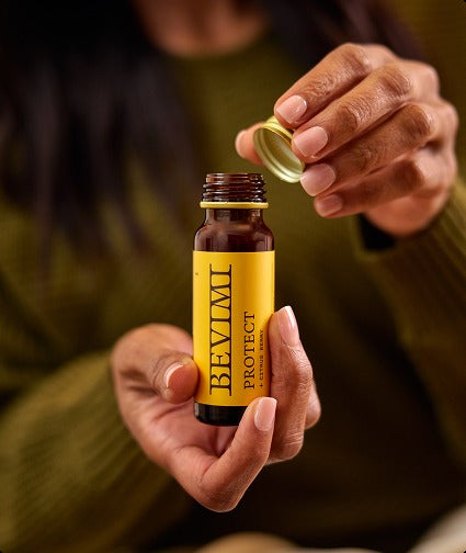 A person holding a Bevimi Uno Protect bottle, twisting off the cap to drink it straight.