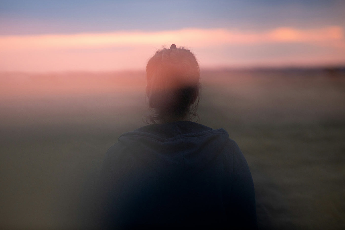 A blurred figure looking out over a hazy landscape
